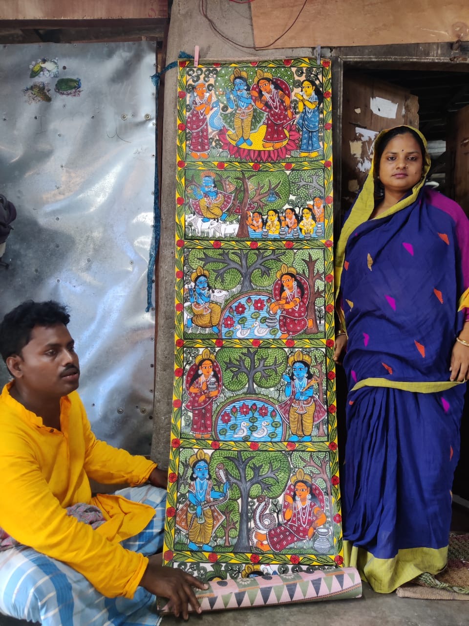 Pattachitra artist Prabir with his wife and a long handpainted scroll outside their home in West Bengal.